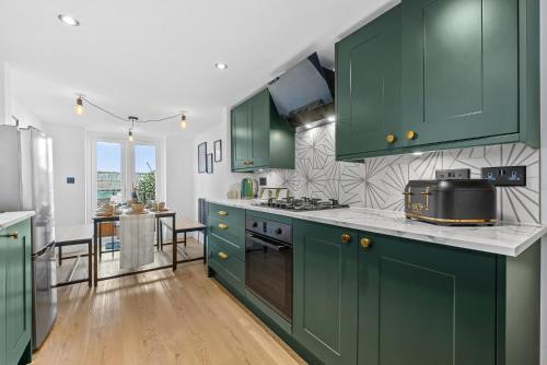 a kitchen with green cabinets and a counter top at Large Luxury 4 Bed Chic House Southampton Centre, Great for groups! Parking available, Sleeps 7- By Blue Puffin Stays in Southampton