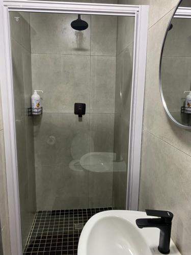 a bathroom with a shower with a sink and a mirror at Black Rose Guesthouse Northam in Northam