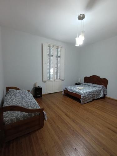 two beds in a room with wooden floors and a window at Renata in Carmelo