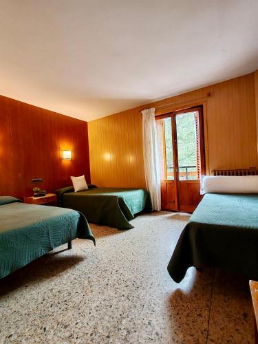 a hotel room with two beds and a window at Hotel Acebo & Natura in Castiello de Jaca