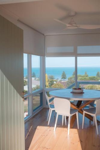 a dining room with a table and chairs and the ocean at Ocean Views Byron Infused Bliss NEW in Encounter Bay