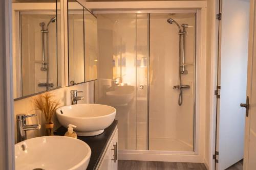 a bathroom with two sinks and a glass shower at Luxus Chalet im schönen Recratiepark De Veerstal in Rheden