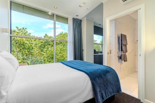 a bedroom with a white bed and a large window at Hamilton Motel in Hamilton