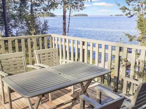 a picnic table and chairs on a deck overlooking the water at Tyyni Resort - Hirsihuvila Aalto in Liperi