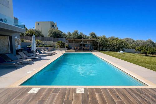 a swimming pool in a backyard with chairs and a table at Villa Aelia - Modern & Ideal for large groups in Galatás