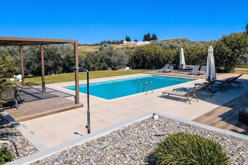 a swimming pool with a table and umbrellas at Villa Aelia - Modern & Ideal for large groups in Galatás