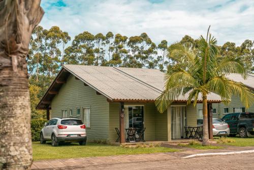 a green house with a palm tree in front of it at Hotel Acqua Lokos in Arroio Teixeira
