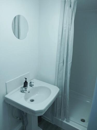 a white bathroom with a sink and a shower at The Commodore Hotel in Nottingham
