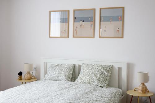 a bedroom with a white bed with four pictures on the wall at Wolf House in Balatonboglár