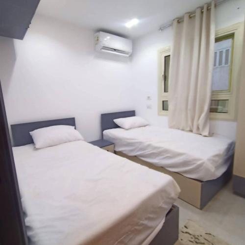 two beds in a room with white sheets and a window at Luna home in Petra