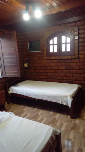 two beds in a room with two windows at Chalé Privê Serrano em Gravatá in Gravatá