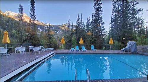 a swimming pool with chairs and a table with a mountain at Condo Right on the Snowbird Slopes! in Sandy