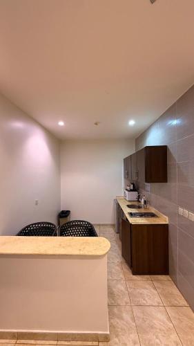 a kitchen with a counter and chairs and a sink at شقق بوابة العالية للشقق الفندقية in Medina