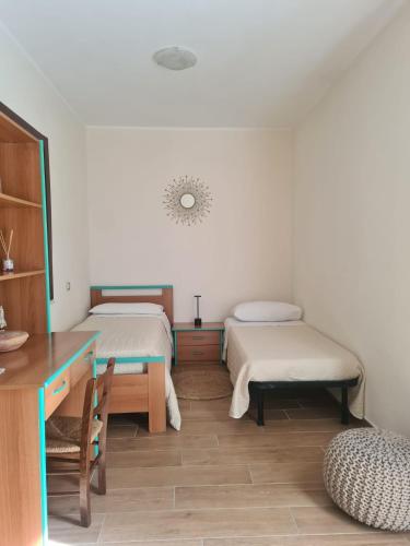 a room with two beds and a table and a desk at Casa Antonella in Sìnnai