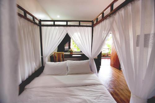 1 cama con cortinas blancas en una habitación en House Of My Eternal Love - Kulai Homestay, en Kulai