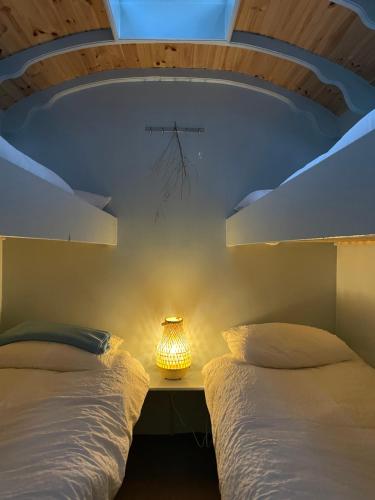 a bedroom with two beds and a lamp on a table at Pipowagen in Haaksbergen