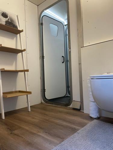 a bathroom with a toilet and a glass door at Pipowagen in Haaksbergen