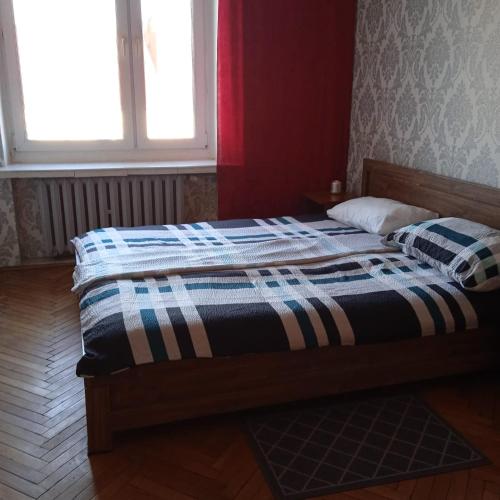 a bed with a striped comforter in a room with a window at Gościnne Gniazdo in Będzin