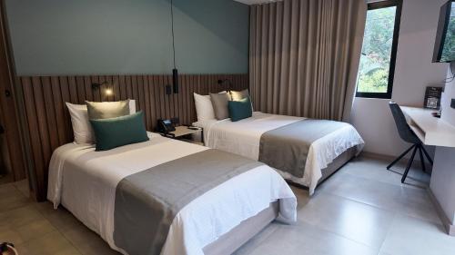 a hotel room with two beds and a window at Hotel Living 35 Suites by Growing Group in Medellín