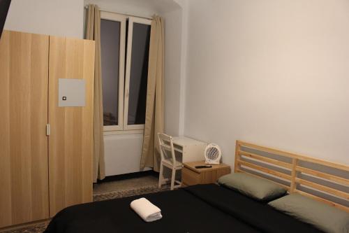 a bedroom with a bed and a chair and a window at Uddin House in Genoa
