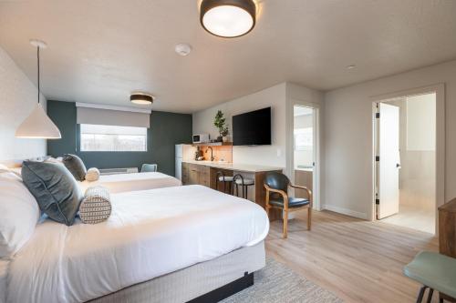 a bedroom with a large white bed and a kitchen at Adobe Desert in Panguitch