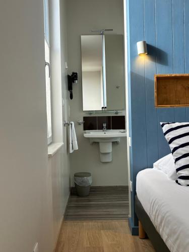 a small bathroom with a sink and a bed at Les Bains Boyardville - Hôtel et Restaurant in Boyard-Ville