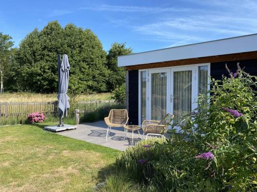 a patio with two chairs and an umbrella and a house at B&B Bed in Burgh in Burgh Haamstede