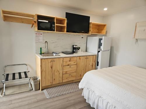 une cuisine avec un lit, un évier et un réfrigérateur dans l'établissement Quest Motel, à Whitewood