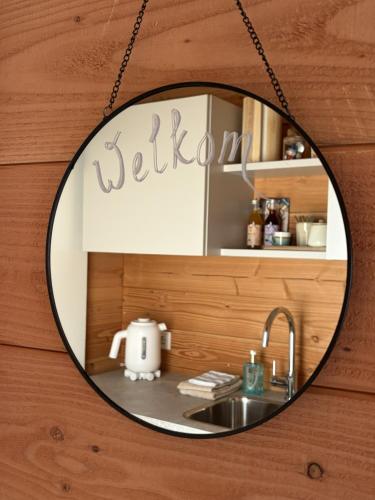 a mirror hanging on a wooden wall with a sink at B&B Bed in Burgh in Burgh Haamstede