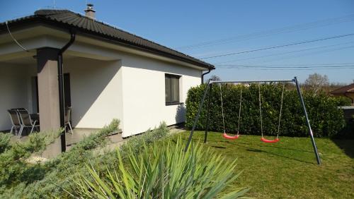 a swing in a yard next to a house at Jenny home in Mojmírovce