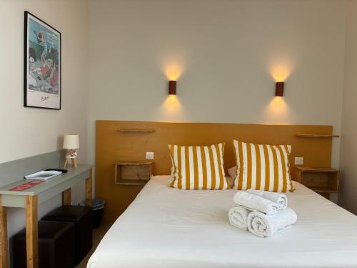 a bedroom with a bed with towels on it at Les Bains Boyardville - Hôtel et Restaurant in Boyard-Ville