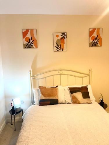 a bedroom with a bed with four paintings on the wall at Wilsuel Haven-2Bedroom Aprt in Wolverhampton