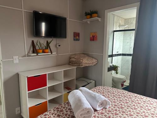 a small room with a bed and a tv on the wall at Pousada Luar in Chapada dos Guimarães