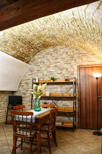 a dining room with a table and chairs and a brick wall at Casa Vacanze Sotto Piazza in Gualdo Tadino