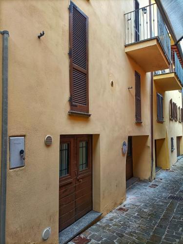 a building with a brown door and a balcony at Casa Vacanze Sotto Piazza in Gualdo Tadino