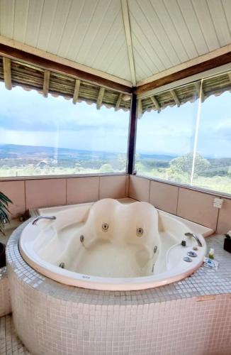 a bath tub with two elephants in a room with windows at Pousada Mirante Serra Verde in Carrancas