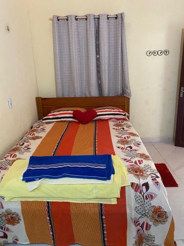 a bed with a colorful blanket with a red bow on it at Pousada da vila in Beberibe