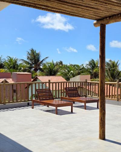 two benches on a deck with palm trees in the background at Portal do Kite in Barra Grande