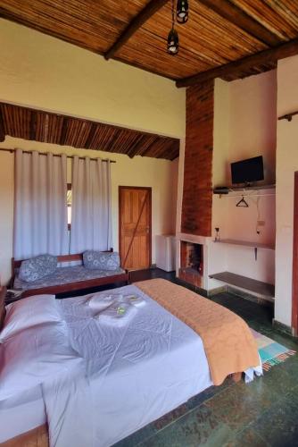 a large bedroom with a large bed and a tv at Pousada Mirante Serra Verde in Carrancas