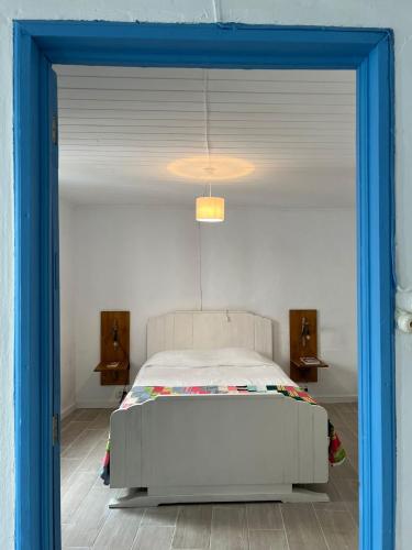 a bedroom with a white bed with a blue frame at Casa Praia do Fogo in Ribeira Quente