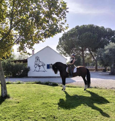 a woman riding a horse in front of a building at Equiliberdade in Quinta de Santa Marta