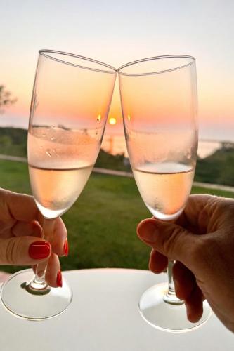 two people holding wine glasses in front of the sunset at BLUE APARTMENT in VILLA ANGISI in Drapia