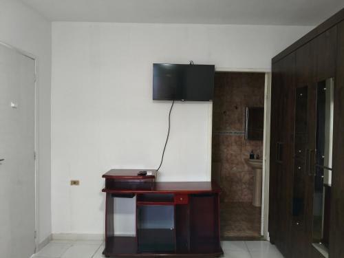 a room with a table with a television on the wall at Flat, primeiro andar, perto do Chevrolet Hall e Centro de Convenções e in Recife