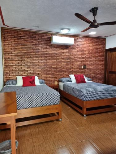 two beds in a room with a brick wall at Casa de Descanso Lolha Bacalar in Bacalar