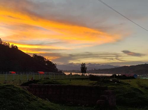a sunset over a field with a body of water at Hospedaje Q'ello Qantu in Coper