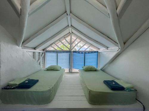 two beds in a room with a window at Hostel La Bohème in Las Terrenas