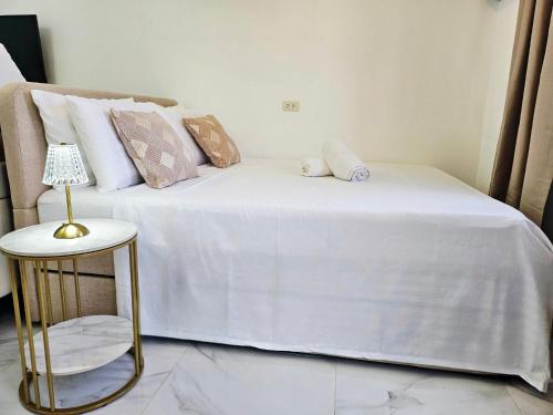 a white bed with pillows and a table with a lamp at AJB Royal Ocean Crest Mactan Cebu in Cebu City