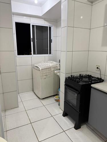 a white tiled kitchen with a stove and a window at Apartamento enseada in Guarujá