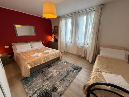 a bedroom with two beds and a red wall at Calle Boldu Venice in Venice