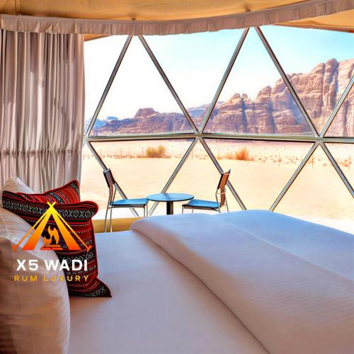 a bedroom with a bed and a view of the desert at X5 wadi Rum Luxury in Wadi Rum